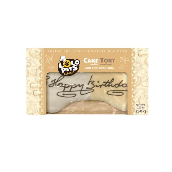 A packaged dog treat bone from Polo Pets Classic, specifically the 'Cake Tort' flavor. The bone is visible through a clear window in the packaging, which features a beige and gold patterned design with 'Happy birthday' written in black script across the front.