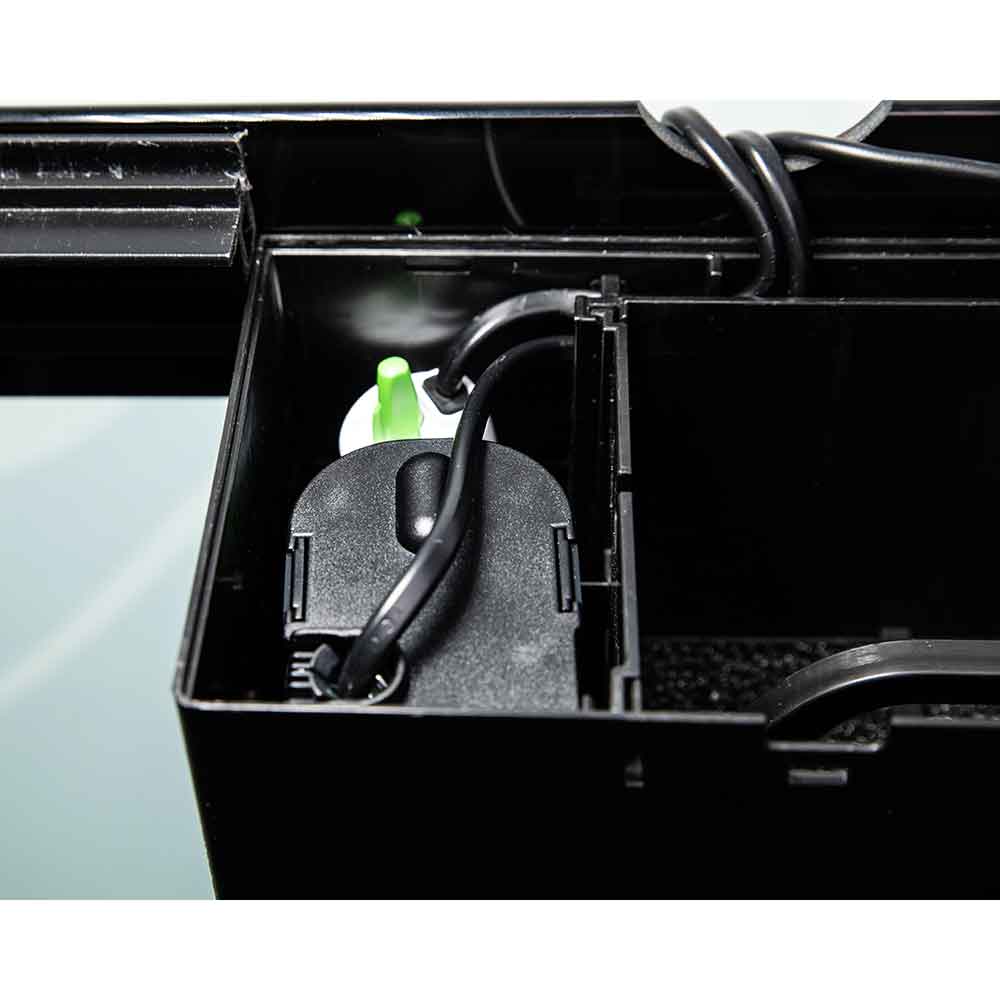 Close-up of a black aquarium filter cartridge and tubing inside an open black filter housing, with a small green cap visible.