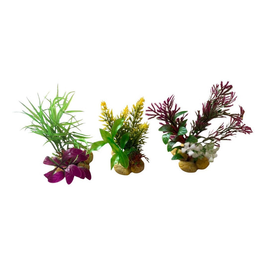 Three artificial aquarium plants with green, yellow, and reddish-purple leaves, each mounted on a small gold-colored base, shown against a plain white background.