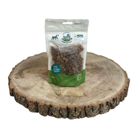 Package of 100 percent natural Nova dog treats on a wooden surface with a white background