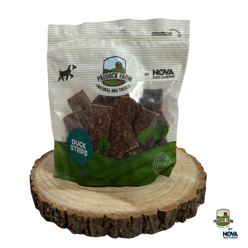 Bag of Paddock Farm duck strips dog treats on a wooden stand with visible branding.