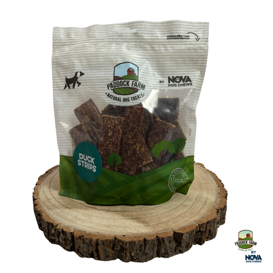 Bag of Paddock Farm duck strips dog treats on a wooden stand with visible branding.