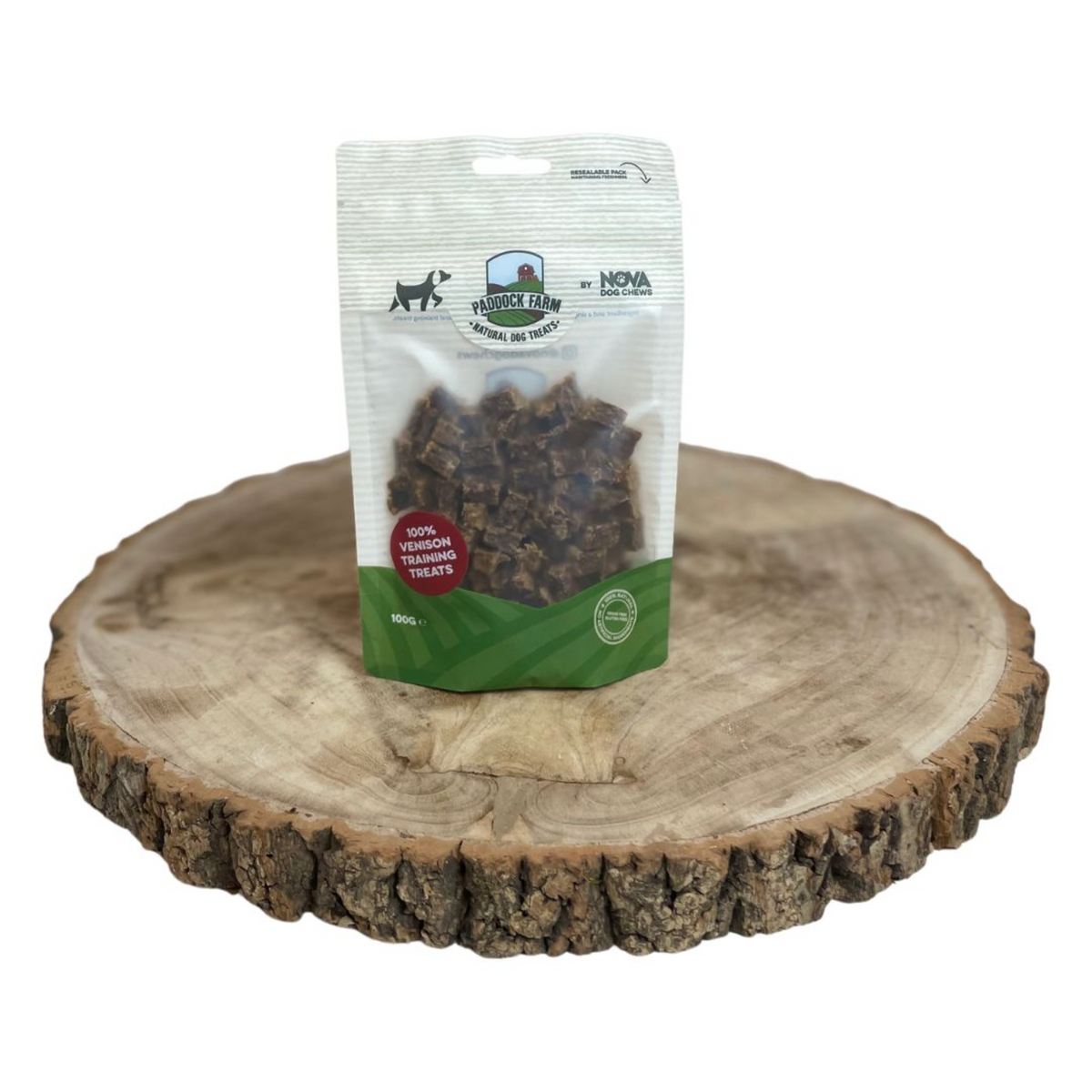 A stand-up pouch of dog training treats placed on a round natural wood slice tray against a plain white background. The package appears to be Nova Farm dog treats, with the brand logo and product window visible.