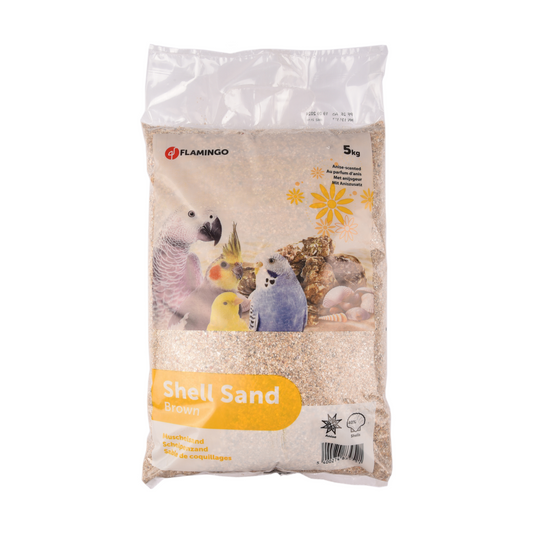A 5kg bag of Flamingo Shell Sand Brown bird substrate, featuring a clear plastic bag with a printed label showing parrots and a yellow sun graphic.