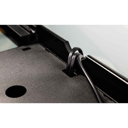 Close-up of a black cable secured in a black loop or clip attached to a dark textured panel with a circular opening, shown against a light gray background.